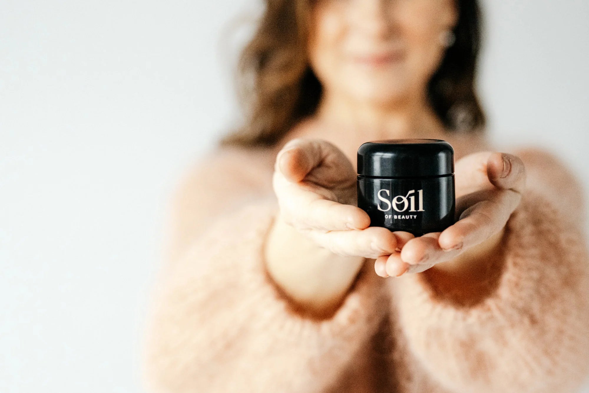 Nainen esittelee Essence Balm kasvobalmia kädessään